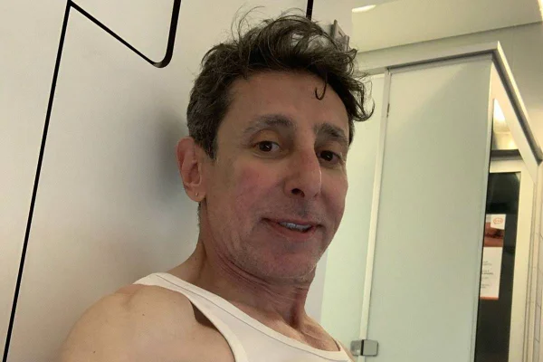 Imagem colorida de Cássio Scapin sorrindo e usando blusa branca - Metrópoles