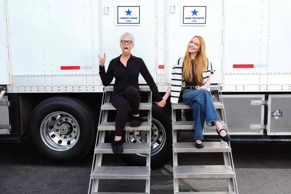 Na imagem colorida, Lindsay Lohan e Jamie Lee Curtis aparecem sentadas em set de gravações - Metrópoles
