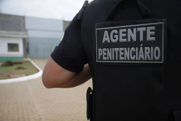 Iamgem mostra agente penitenciário, de costas, em frente à unidade prisional - Metrópoles