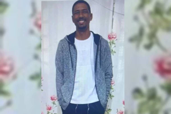 Alex Brito Alves da Cruz. Homem de camiseta branca, casaco aberto cinza, mãos no bolso - Metrópoles