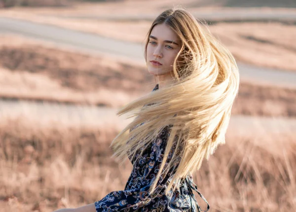 Fotografia colorida mostrando mulher balançando o cabelo no ar no meio do mato-Metrópoles