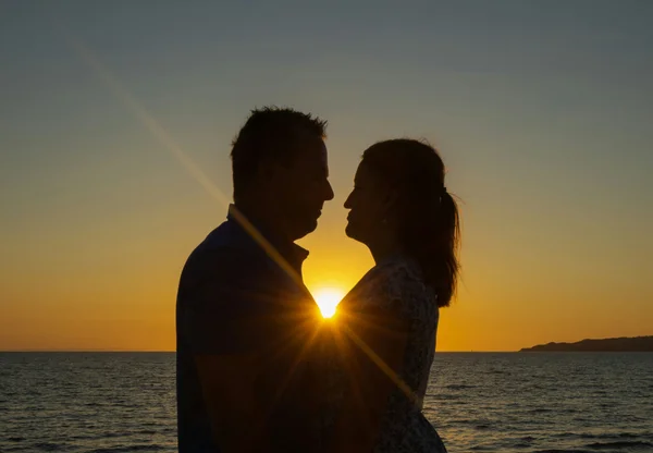 Fotografia colorida mostrando casal com por do sol atrás-Metrópoles