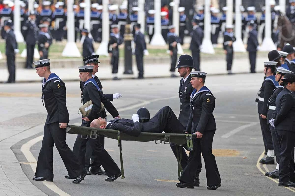 Um homem de uniforme é carregado em uma maca antes do funeral de estado da rainha Elizabeth II na Abadia de Westminster em 19 de setembro de 2022 em Londres, Inglaterra. Os membros do público podem prestar homenagem a Sua Majestade a Rainha Elizabeth II durante 23 horas por dia, das 17:00 de 18 de setembro de 2022 às 06:30 de 19 de setembro de 2022. A Rainha Elizabeth II morreu no Castelo de Balmoral, na Escócia, em setembro 8, 2022, e é sucedida por seu filho mais velho, o rei Carlos III