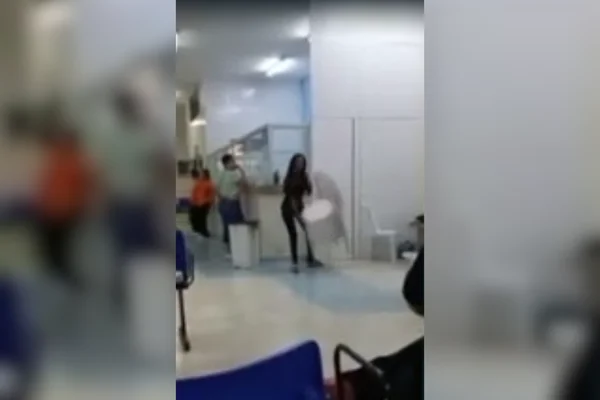 Imagem colorida de uma mulher derrubando cadeiras de plástico em um pronto-socorro - Metrópoles