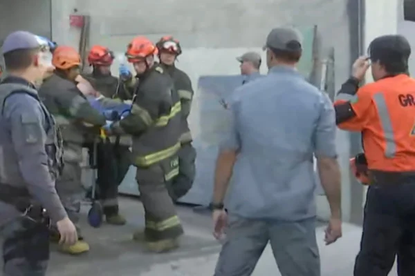 Imagem colorida de homem sendo socorrido pelos bombeiros. Metrópoles