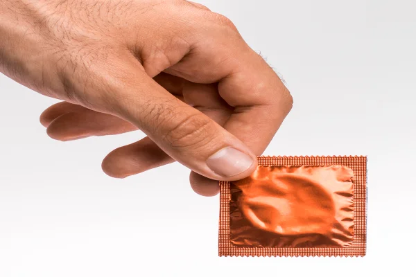 Mão segurando camisinha/sexo- Metrópoles
