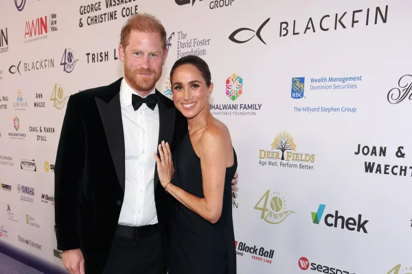 Foto colorida de homem de fraque abraçado a mulher de vestido preto - Metrópoles