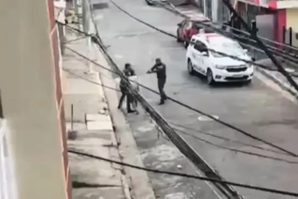 Imagem colorida mostra momento em que homem é baleado ao tentar pegar arma de policial. Metrópoles