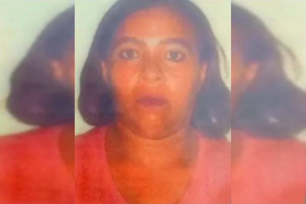 Maria Ivonilde Abreu. Mulher olha para foto 3 por 4. Ela veste camisa rosa e usa batom vermelho