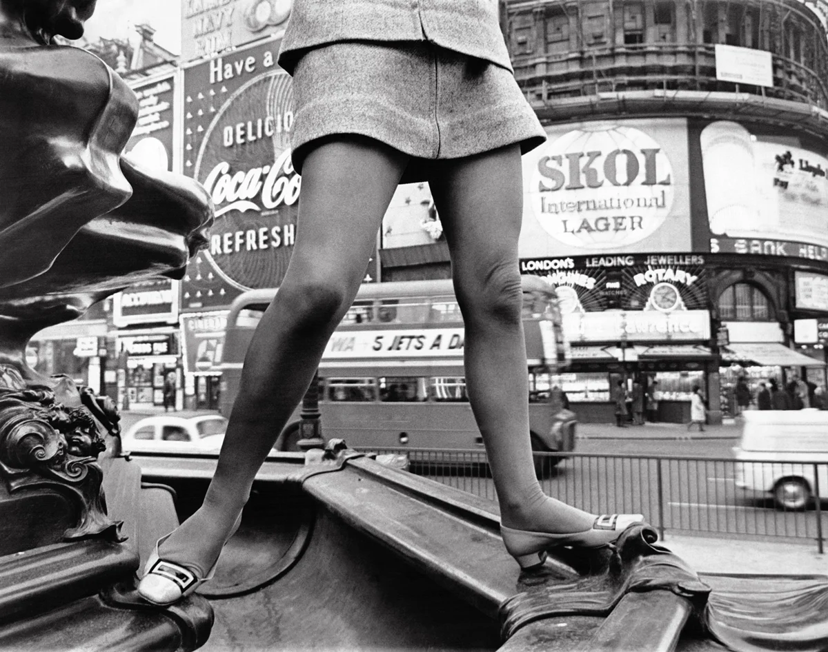 Mulher usando minissaia e sobre a fonte de Piccadilly Circus, em Londres, na Inglaterra, Reino Unido, em 14 de fevereiro de 1967 Mulher usando minissaia e sobre a fonte de Piccadilly Circus, em Londres, na Inglaterra, Reino Unido, em 14 de fevereiro de 1967