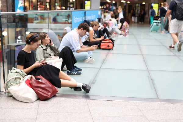 Pessoas sentadas no chão com malas - Metrópoles