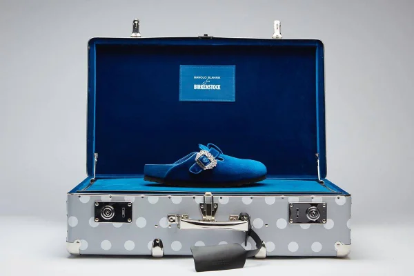 Mule azul com uma tira com adorno de brilhantes dentro de uma mala semi aberta