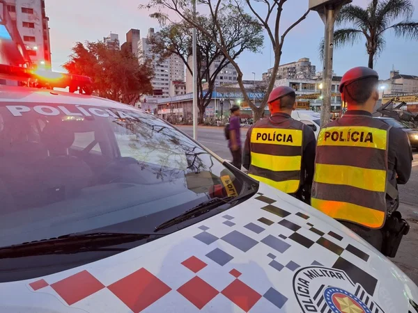 Imagem mostra viatura da PM e dois policiais militares de costas - Metrópoles