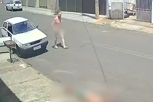 Imagem colorida mostra homem pelado ao lado de carro branco no meio da rua - Metrópoles
