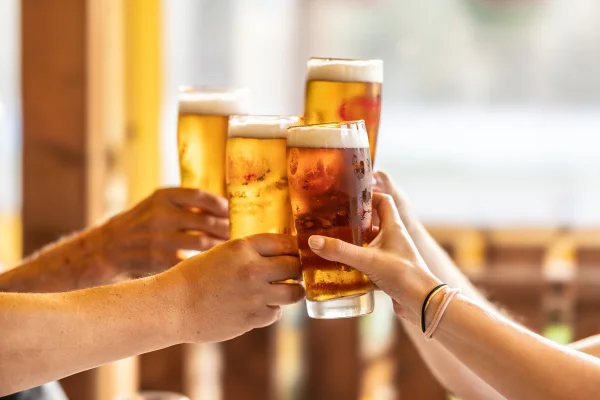 Grupo de 4 pessoas brinda com copos de cerveja - Metrópoles