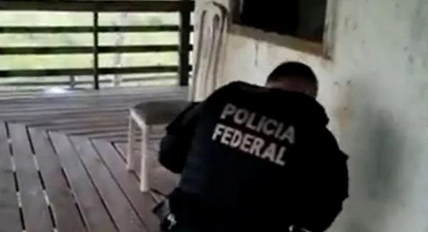 policial federal confere artefatos que estão no chão de uma casa branca. ele usa o uniforme da PF