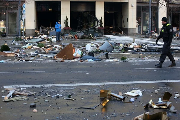 Rua com destroços de aquário cilíndrico do Radisson destruído, em Berlim, com 1.500 peixes. Na imagem se vê bombeiros trabalhando no local - Metrópoles