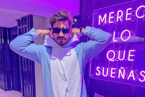 na foto vemos um homem com um macacão azul de moletom e oculos escuros