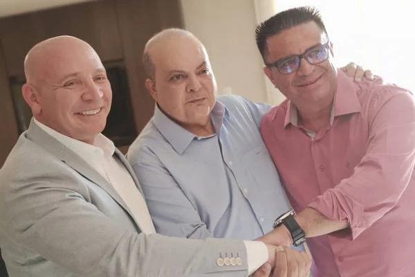 Fotografia colorida de três homens dando as mãos