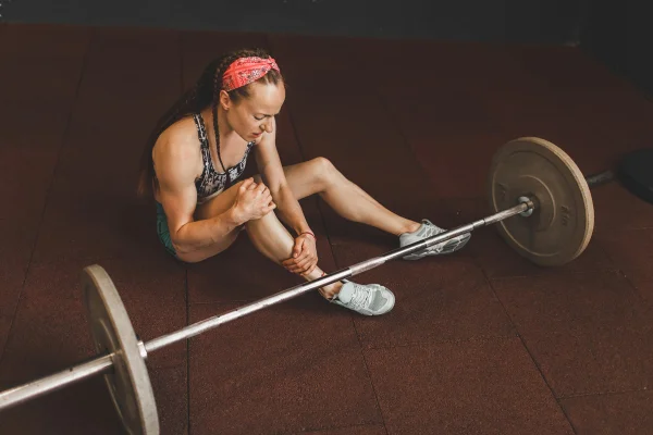 Lesão no joelho de mulher levantando barra no ginásio. Problema de saúde, entorse ligamentar, estresse e dor, lesão