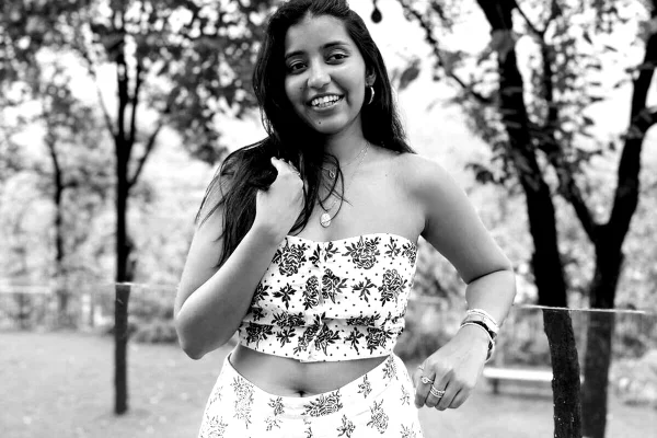 Aanvi Kamdar posa, sorridente, de cabelos soltos e look floral - Metrópoles