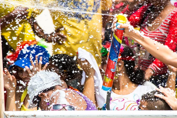 Imagem mostrando pessoa jogando spray de espuma em meio a multidão no Carnaval - Metrópoles