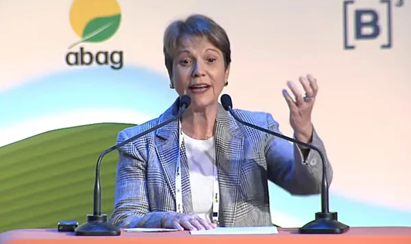 Imagem da ex-ministra da Agricultura Tereza Cristina falando ao micofrone durante congresso sobre agronegócio. Ela veste um terno claro e tem a mão esquerda levantada - Metrópoles