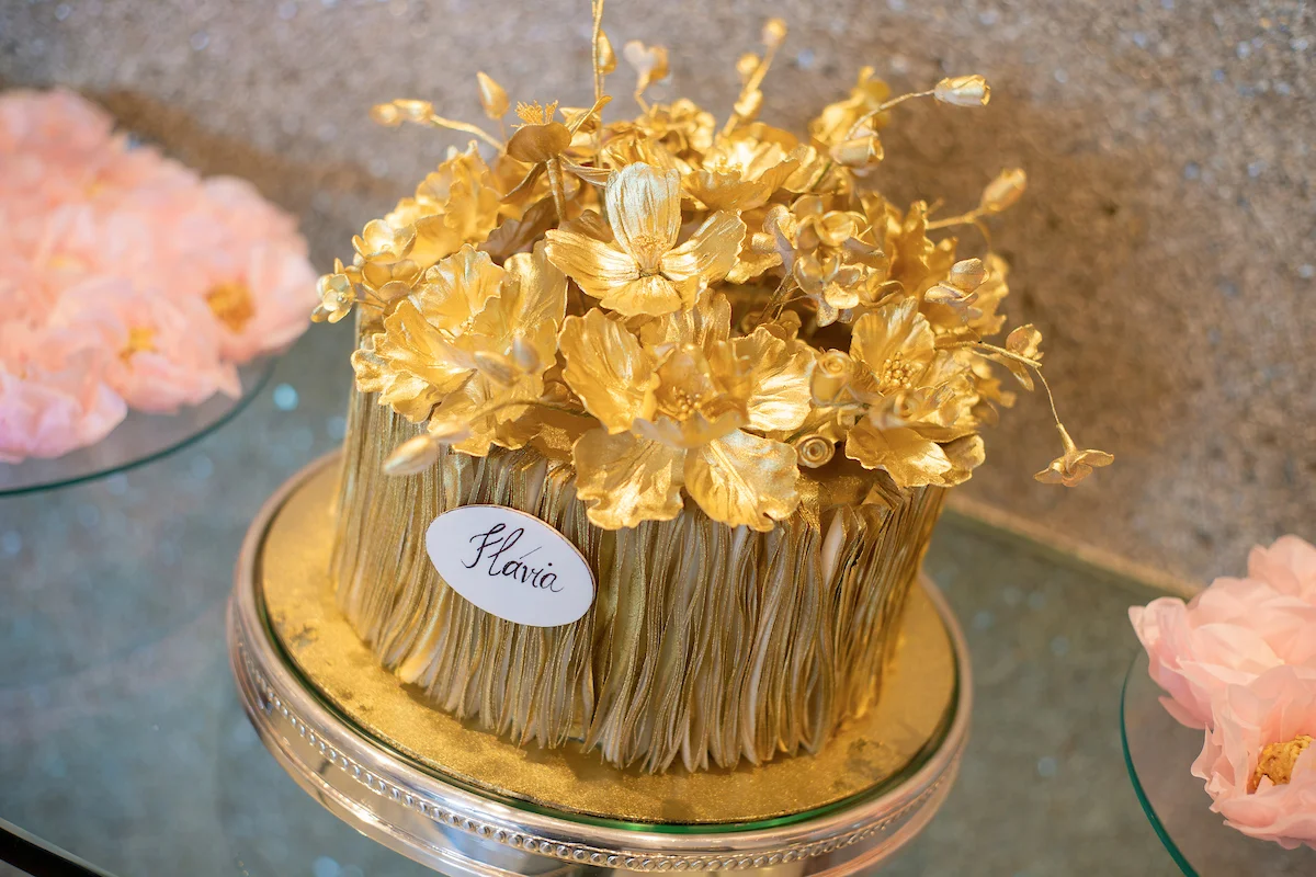 Para o bolo, tons de dourado e decorações florais sofisticadas Para o bolo, tons de dourado e decorações florais sofisticadas