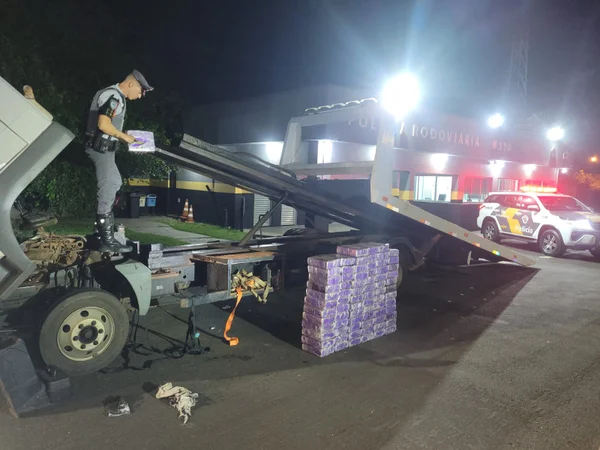 Imagem colorida mostra policial em cima de um caminhão com guincho que transportava maconha; homem que dirigia o veículo foi preso - Metrópoles