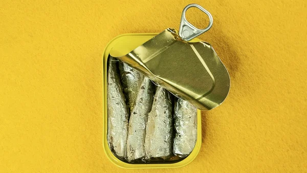 O ômega 3 auxilia a controlar vontade de doce: foto colorida de lata de sardinha sobre fundo amarelo