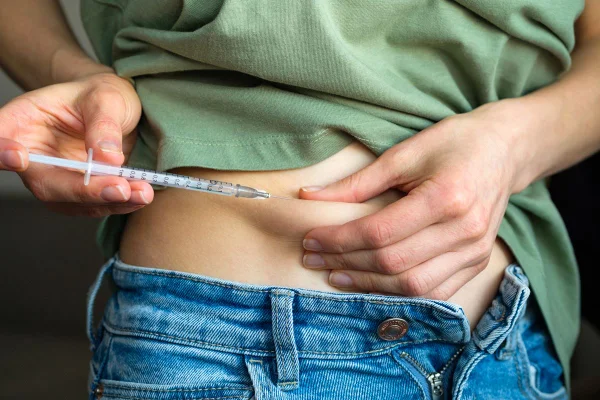 Uma mulher com diabetes puxa a pele da barriga e aplica uma injeção de insulina com uma seringa descartável com uma agulha pequena, ou uma menina que planeja uma gravidez estimula a ovulação antes da inseminação artificial ou concepção - Metrópoles