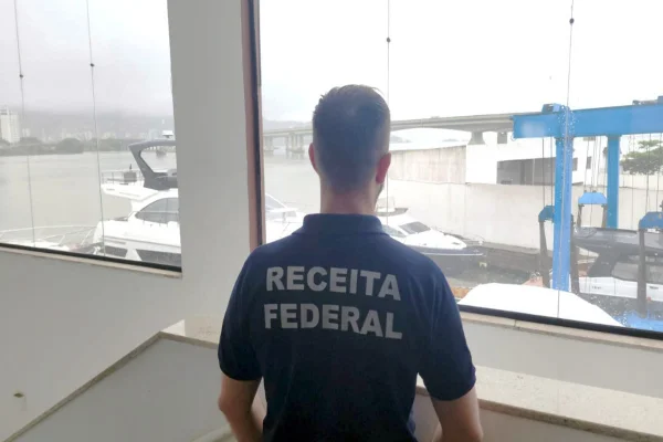 Imagem colorida, Policial Federal em porto com barcos - Metrópoles