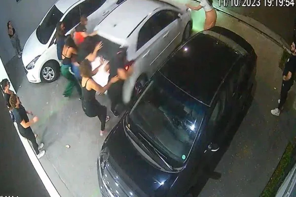 Frame de câmera de segurança mostra motorista dando ré em um carro e atropelando as pessoas atrás dele. Imagem mostra pessoas ao redor do carro no momento do atropelamento - Metrópoles