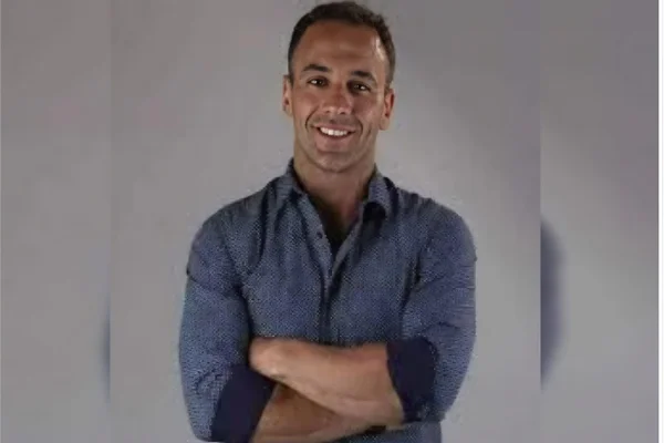 Imagem colorida, homem de braços cruzados sorrindo - Metrópoles
