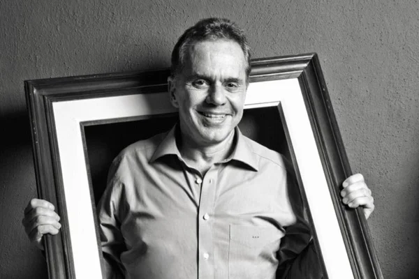 Imagem do ex-banqueiro Edemar Cid Ferreira segurando um quadro e sorrindo - Metrópoles
