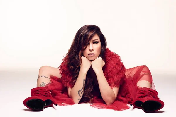 cantora pitty sentada de vestido vermelho fazendo cara séria - metrópoles
