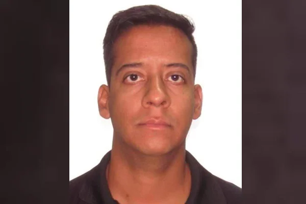 Homem em foto 3 x 4 de gola polo preta e fundo branco