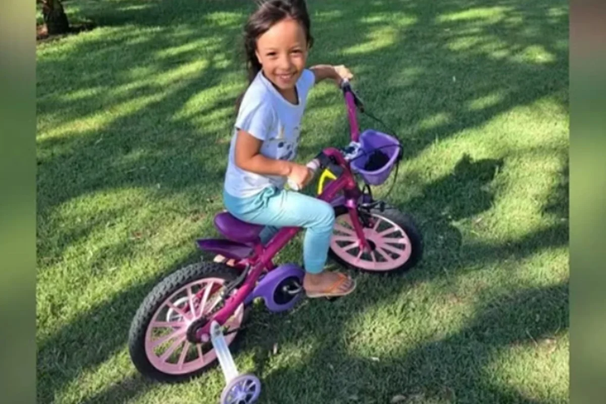 Imagem colorida de criança em cima de uma bicicleta