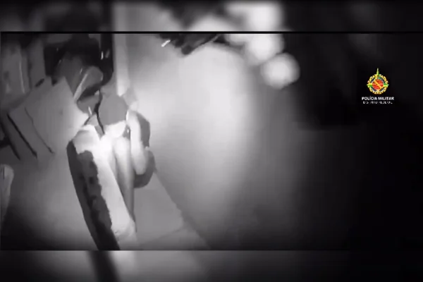 Imagem em preto e branco de um homem sentado com as mãos atrás do pescoço