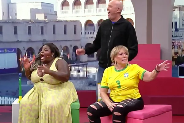 Jojo Todynho, sentada no estúdio do Central da Copa, ri de comentário de Susana Vieira, vestida com a camisa da seleção brasileira - Metrópoles