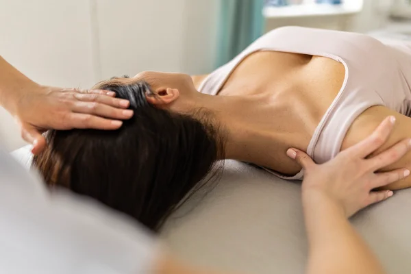 Imagem mostra mãos alongando o pescoço de uma mulher, que está deitada passando por uma sessão de quiropraxia - Metrópoles