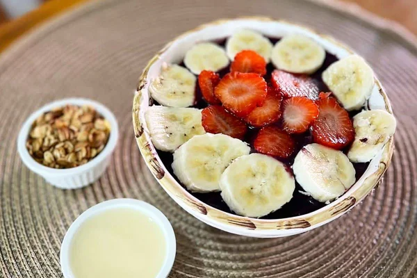 Na foto vemos uma cumbuca de açaí com bananas e moangos e dois potinhos menores