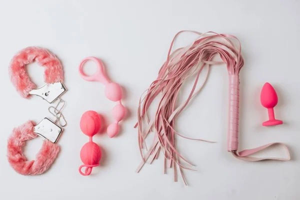 Foto colorida de 5 sex toys cor de rosa espalhados em um fundo branco - Metrópoles