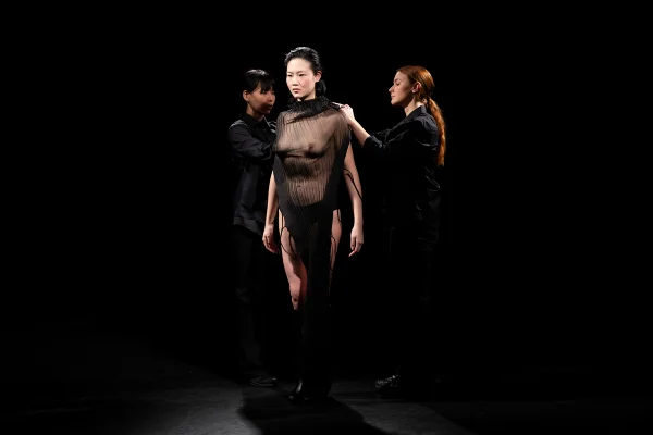 Na imagem com cor, modelo seminua tem vestido montado ao vivo na passarela - Metrópoles