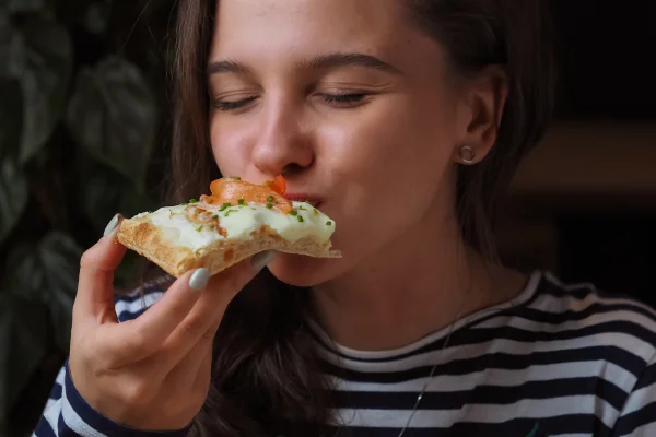 Na foto uma mulher come uma pizza - Metrópoles