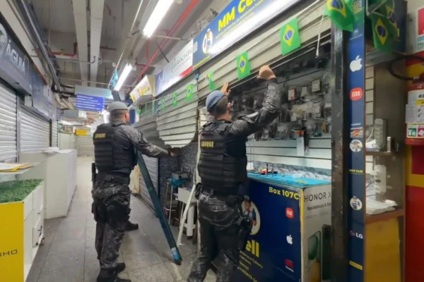 Imagem colorida mostra policiais em frente a loja de celulares. Metrópoles