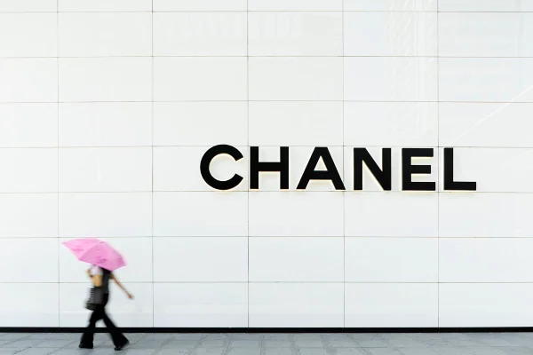 Pessoa andando em fachada de loja Chanel com guarda-chuva - Metrópoles