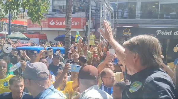 Jair Bolsonaro em campanha no RJ na reta final da campanha, acenando para uma multidão de apoiadores em rua - Metrópoles