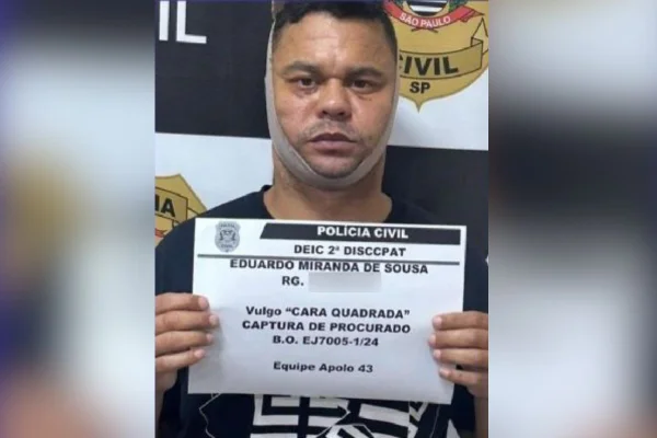 Imagem colorida mostra homem conhecido como "Cara Quadrada" com um papel de identificação na mão e curativo ao redor do rosto - Metrópoles