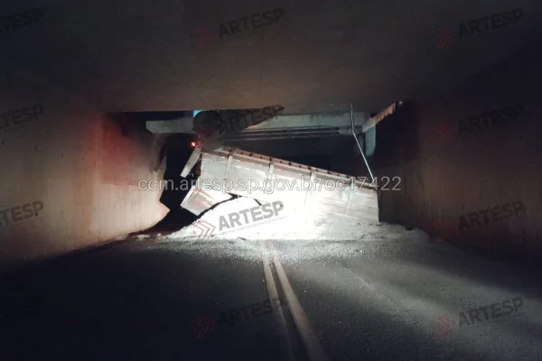 Imagem colorida de carreta tombado em viaduto. Metrópoles